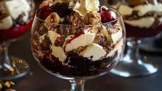 three desserts in glasses on a table with nuts and other toppings around them