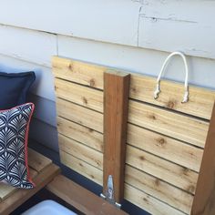 a wooden bench sitting next to a wall with two pillows on it's sides