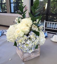 a wooden box filled with white flowers on top of a table covered in blue and white napkins