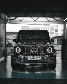 a mercedes benz g - class is parked in a garage with its hood up and lights on