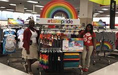 two women standing in front of a table with t - shirts and rainbows on it