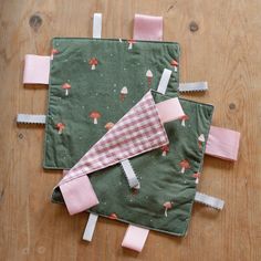 two pieces of fabric with pink and green designs on them sitting on a wooden table