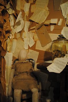 a doll sitting on a chair in front of a pile of papers