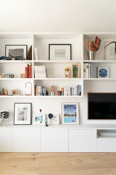 a living room filled with lots of white furniture and bookshelves above a flat screen tv