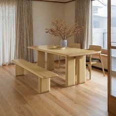 a wooden table with two benches in front of it and a vase filled with flowers