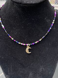 a necklace that has a crescent on it with beads around the neck and a gold charm