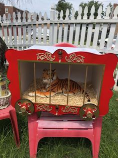 a red and gold painted dollhouse with a tiger in it's cage on the grass