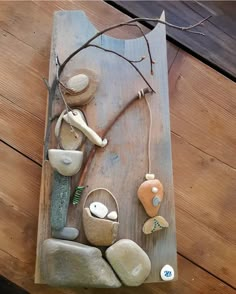 a wooden wall hanging with rocks and shells on it's sides, along with a tree branch