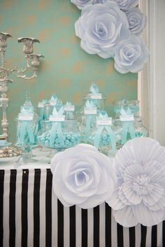 a table topped with lots of cake covered in frosting and white flowers next to a chandelier