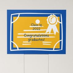 a blue and yellow graduation sign hanging from the side of a white wall with an award on it