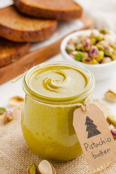 a jar filled with pistachio butter next to bread