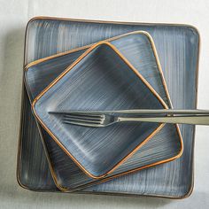 three square plates with silverware on them, one has an orange stripe around the edge