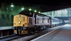 a yellow train is coming down the tracks at night in an underground station with lights on