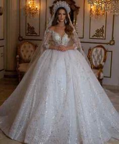 a woman in a white wedding dress standing next to a chandelier