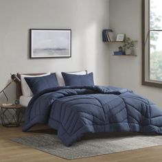 a bed with blue comforter and pillows in a room