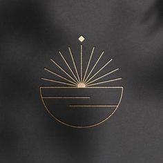 a black and gold logo with the sun in it's center on a dark background