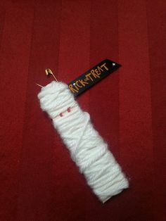 a white piece of yarn sitting on top of a red surface