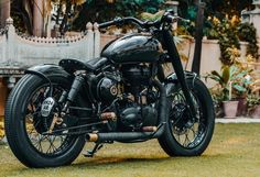 a black motorcycle parked on top of a lush green field