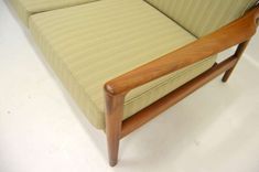 a close up of a couch on a white floor with a wooden armrests