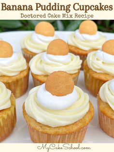 cupcakes with white frosting and orange decorations on a platter in front of greenery