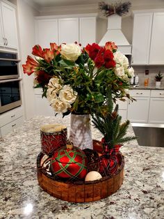 a vase filled with red and white flowers on top of a counter next to candles