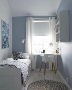 a bedroom with a bed, desk and window in the corner next to a rug