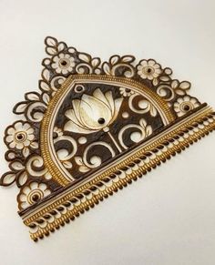 an intricately designed brooch with gold and white flowers on it's side