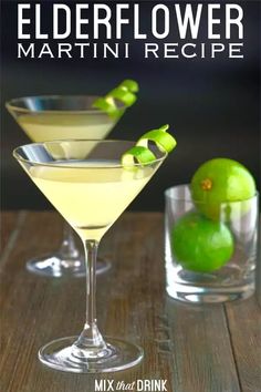 two martini glasses with limes in them on a wooden table next to each other