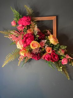 an arrangement of flowers is placed in front of a frame