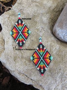 a pair of beaded earrings sitting on top of a rock