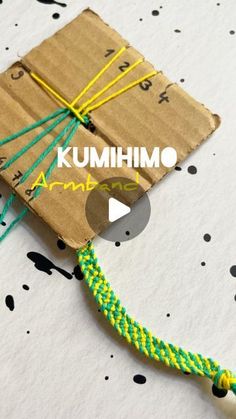 an origami kite made out of brown paper and green string with the words kumhimo on it