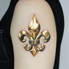 a gold fleur de lis tattoo on the arm