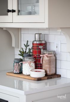 some jars are sitting on a cutting board in the middle of a kitchen counter top