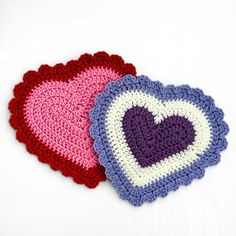 two crocheted heart coasters sitting next to each other on a white surface