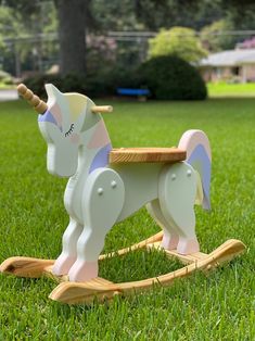 a wooden rocking horse sitting in the grass