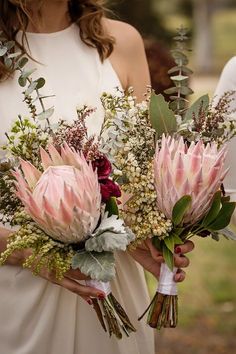 a bride holding two bouquets of flowers in her hands