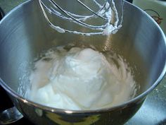 a mixing bowl filled with whipped cream on top of a counter