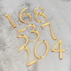 gold numbers and numerals are laid out on a gray surface, with one number in the middle