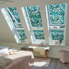 a bedroom with stained glass windows in the ceiling and bed on the far side, next to a wooden floor