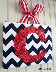 a red and white chevroned ribbon hanging on a wall with buttons in the shape of a heart