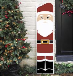 a christmas door hanger with a santa clause standing in front of a decorated tree