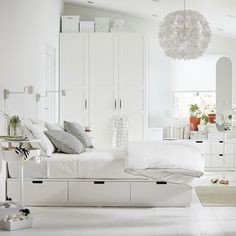 a white bedroom with lots of furniture and accessories on the bed in front of it