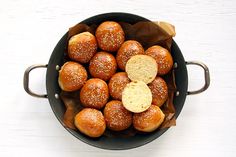 a pan filled with buns sitting on top of a white table next to bread