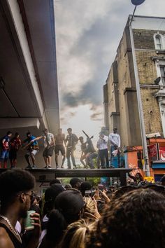 a group of people standing on top of a wooden platform in the middle of a crowd