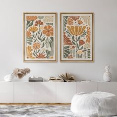 two paintings hang on the wall above a white cabinet in a room with fur rugs