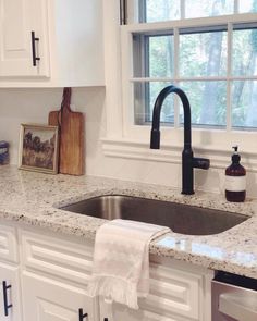 a kitchen sink under a window next to a wooden cutting board and utensils