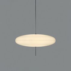 a white light hanging from a ceiling in a room with gray walls and flooring