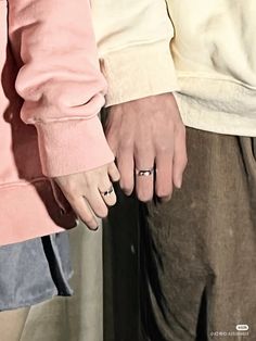 two people standing next to each other with their hands on one another's fingers