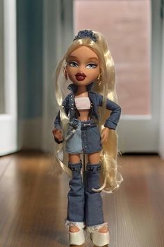 This Always Bratz doll, Cloe, is a stylish 9-inch figure with very long blonde curly hair. She is dressed in a standout jean outfit adorned with embellishments and buttons, complemented by large hoop earrings. Chloe's accessories include a brush, a purse, a cell phone, a necklace, lip gloss, hair clips, and pink sunglasses. Additionally, she comes with a free poster. The doll is brand new in the box, having only been removed for photographs, and is in pristine condition with no rips, stains, or tears. This doll is a perfect addition for collectors and fans of Bratz. DS Bratz Cloe Outfit, Brunette Bratz Doll, Bratz Doll Costume, Blonde Bratz, Bratz Hair, Chloe Bratz, Bratz Aesthetic Outfit, Cloe Bratz, Bratz Cloe