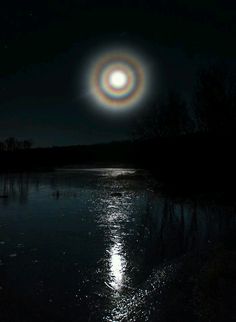 the moon is shining brightly in the dark sky over a body of water at night